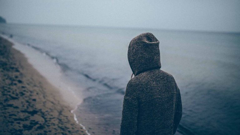 Sad person overlooking ocean alone
