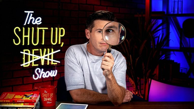 Kyle Winkler at desk with magnifying glass over one eye.