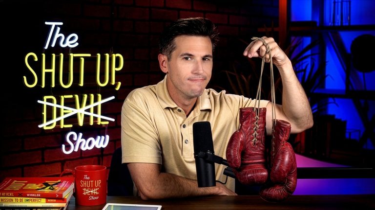 Kyle Winkler at desk with pair of boxing gloves dangling from hand